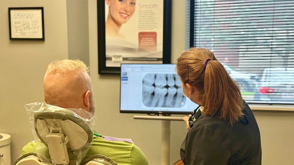 Dentist showing a male patient an x-ray image of teeth on a screen
