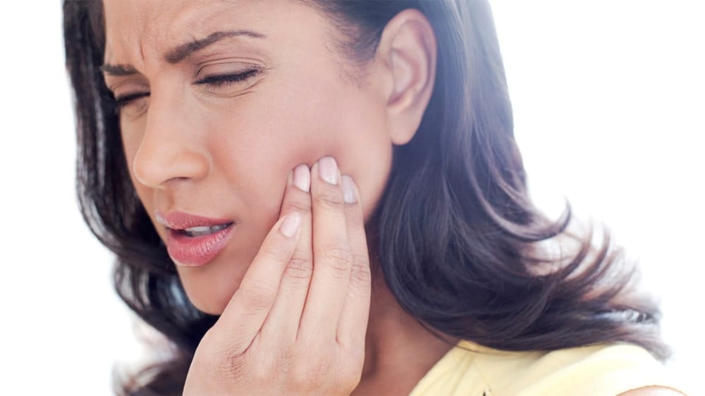 Woman touching her jaw with a pained expression due to facial discomfort