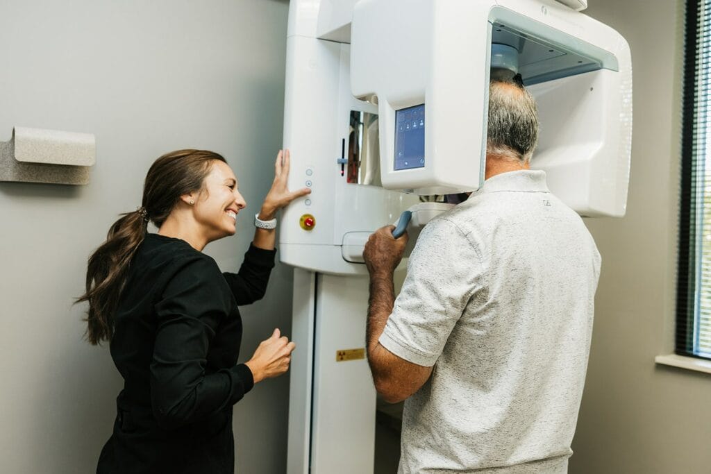 Male patient getting a panoramic dental scan while a dental assistant operates the machine