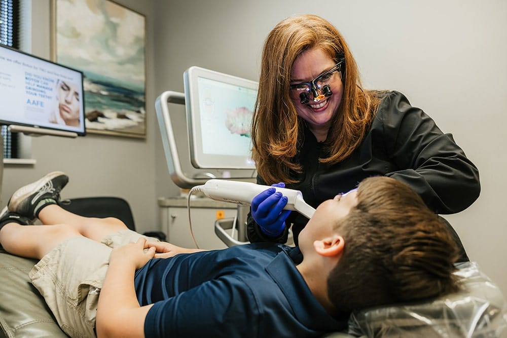 Dentist using a digital scanner on a young patient in a dental chair