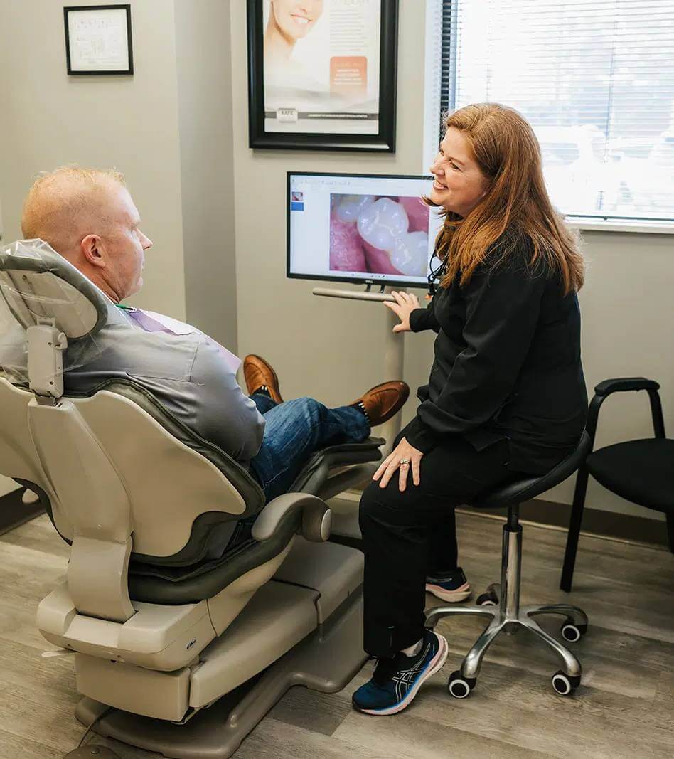Dental professional showing a patient an image of their tooth on a monitor during a consultation