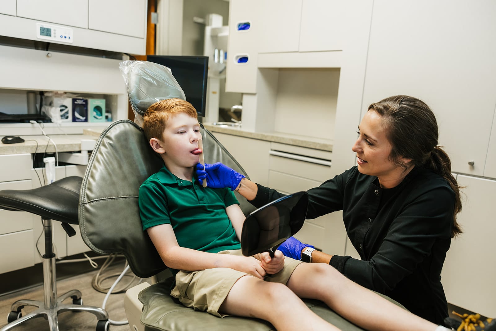 Young boy sticking his tongue out during a dental checkup with Dr. Stephanie Briggs