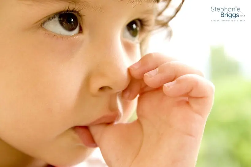 Cute young girl sucking her thumb in a close-up photo